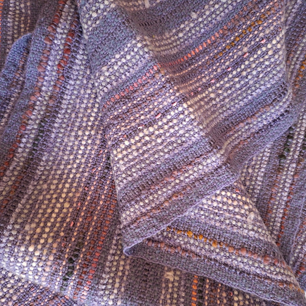 A close-up of a textured woven fabric with a heathered lavender-mauve base and subtle pink, white, and gray variegated stripes.